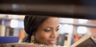 Smiling girl examining book in library
